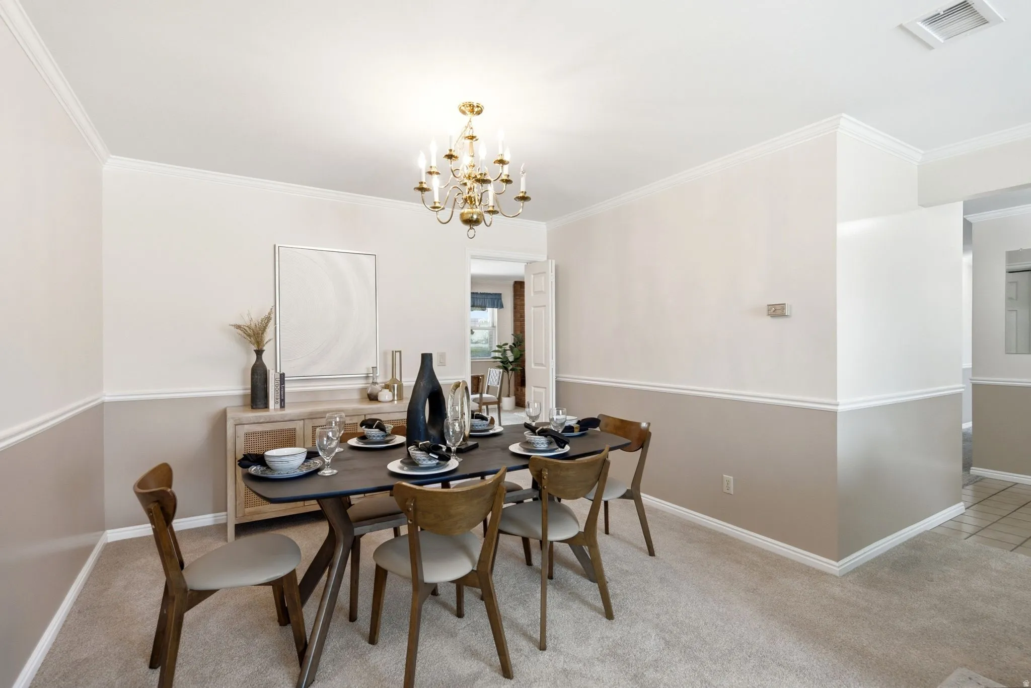 Dining area featuring crown molding, two-tone wall treatment, and carpet flooring