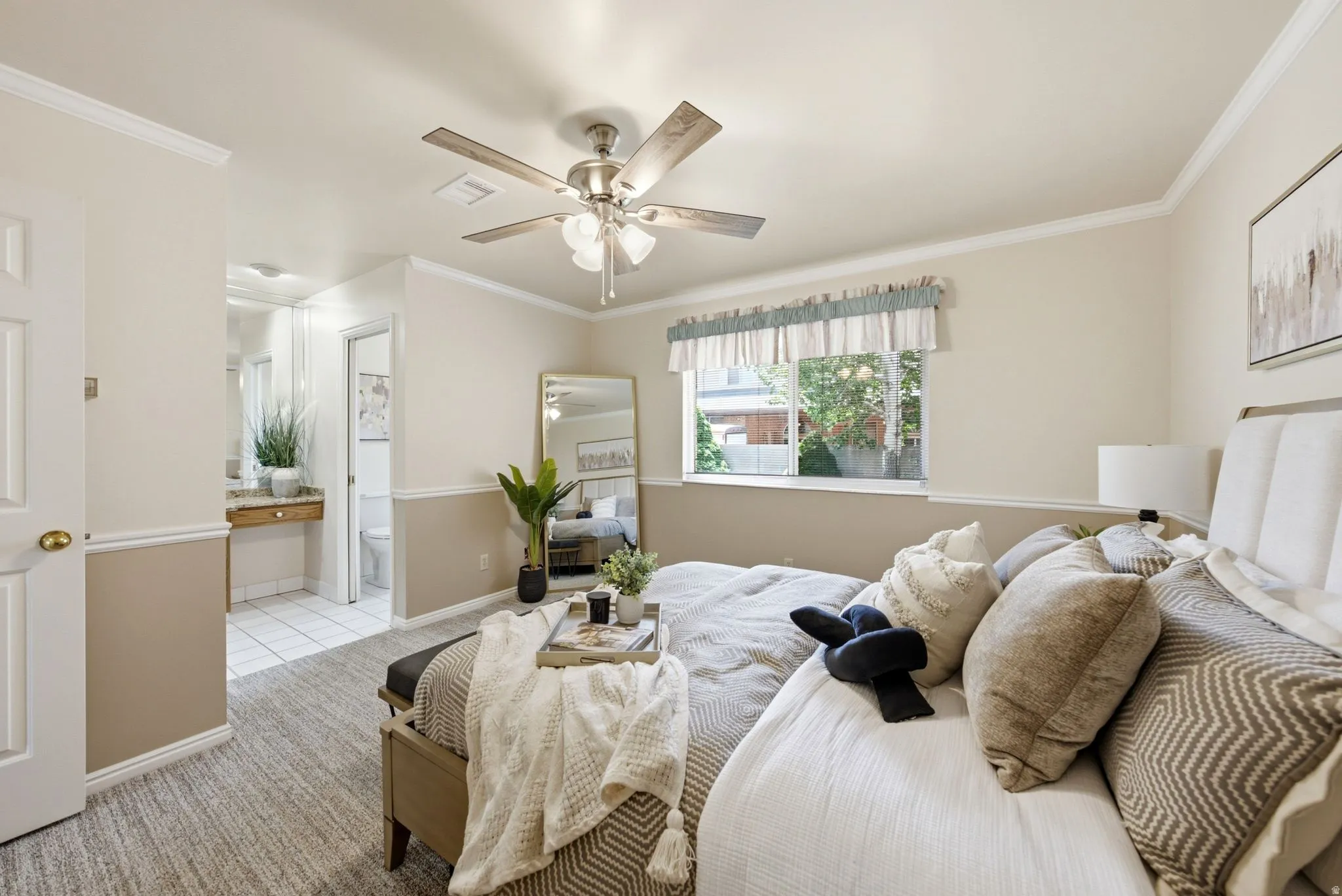 Carpeted room with a ceiling fan, crown molding, and a window with a valance