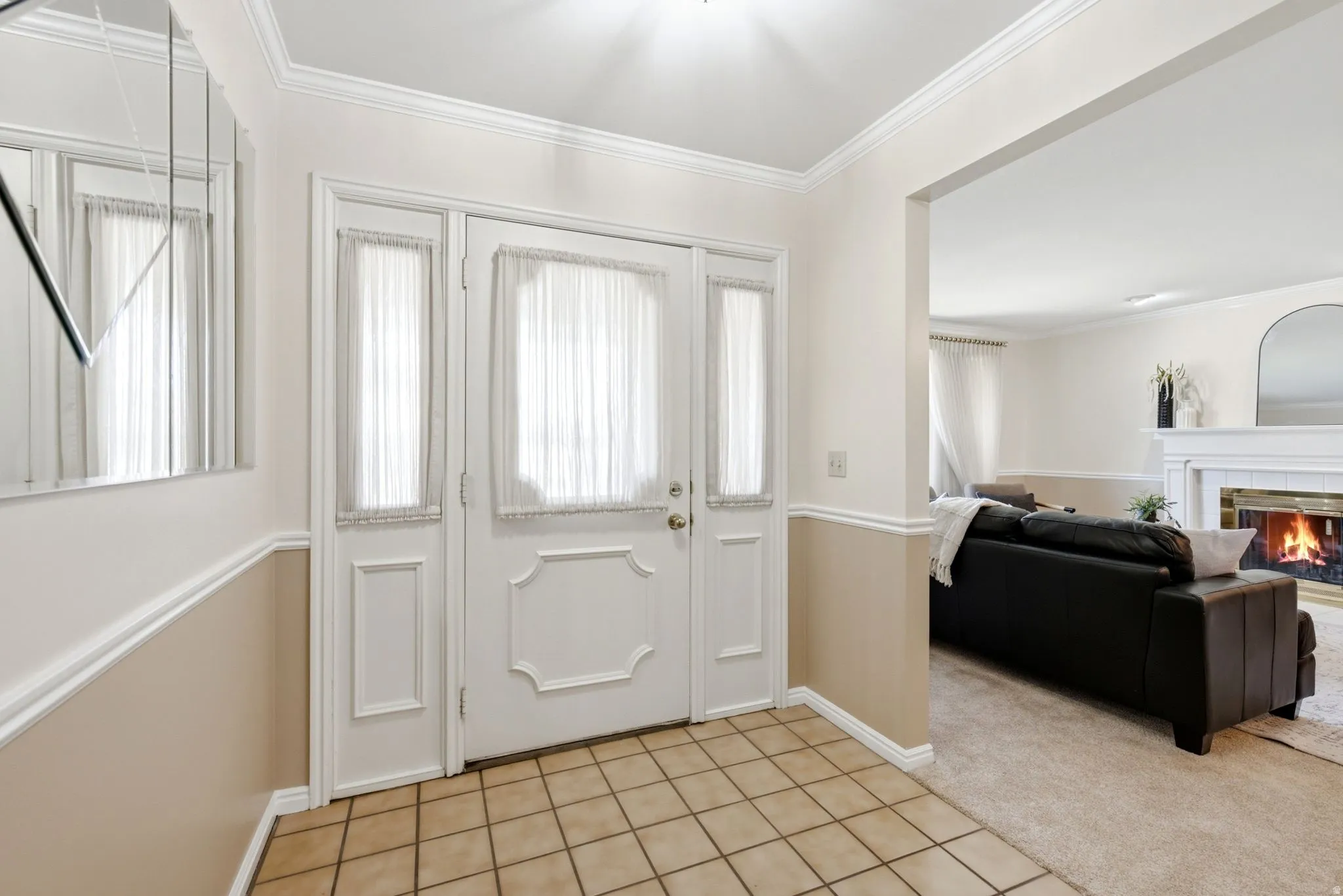 Entryway featuring tile flooring, white wainscoting, and a paneled entry door with sidelights