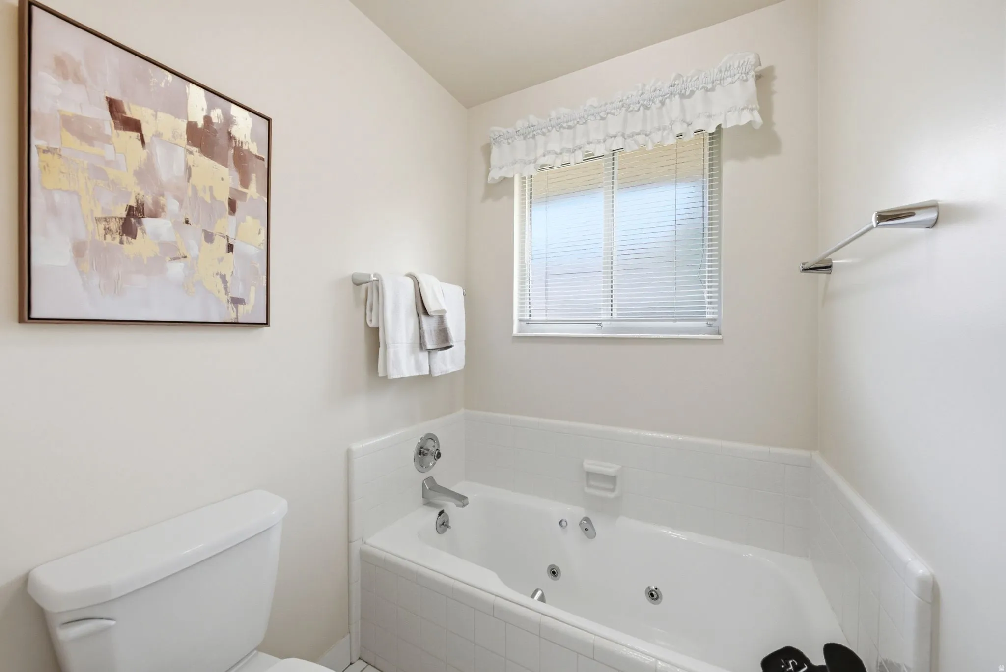 Soaking tub with jetted features, white ceramic tile surround, and an integrated window