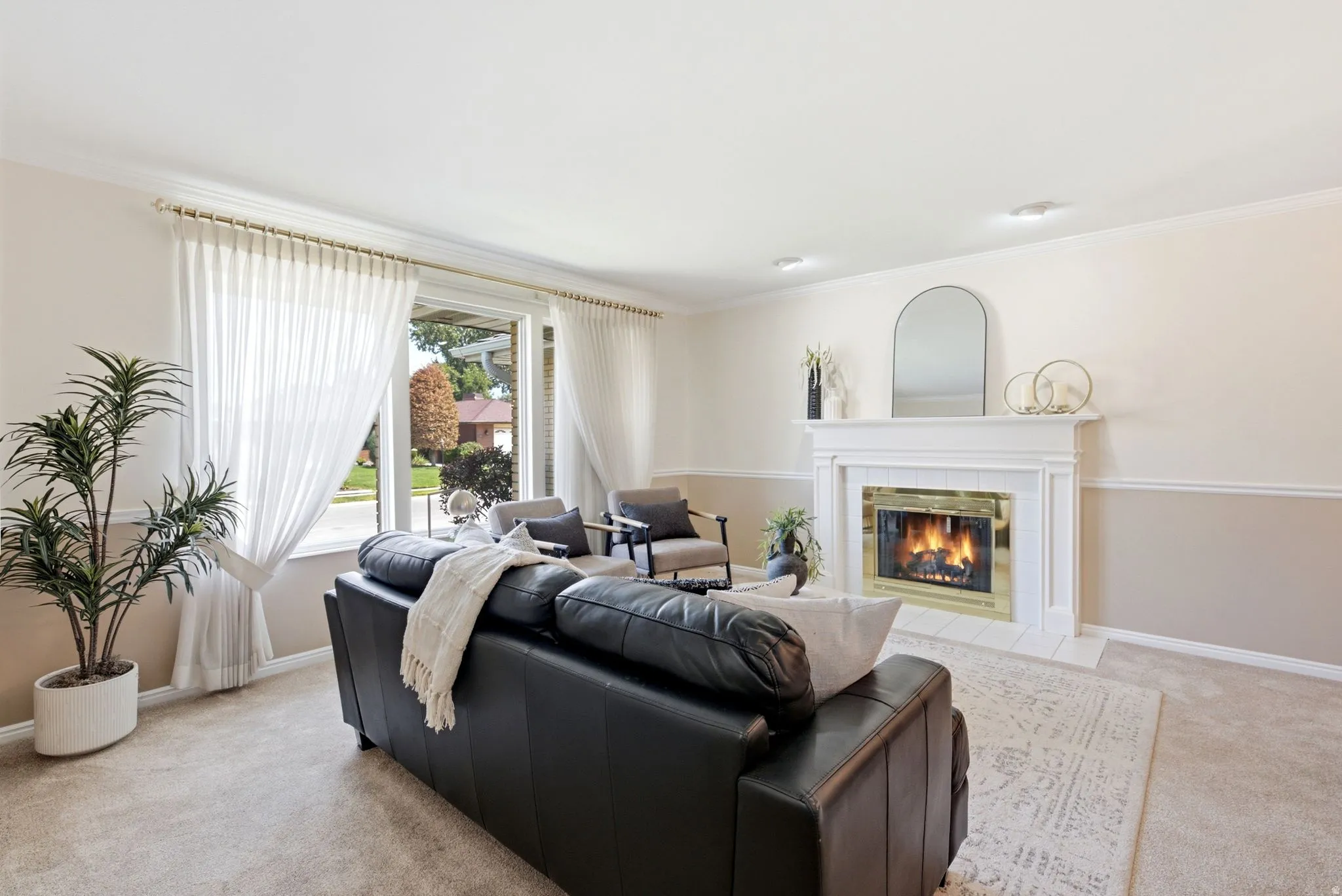 Living area featuring a white mantel fireplace with a gold-toned insert, a large picture window, crown molding, and recessed lighting