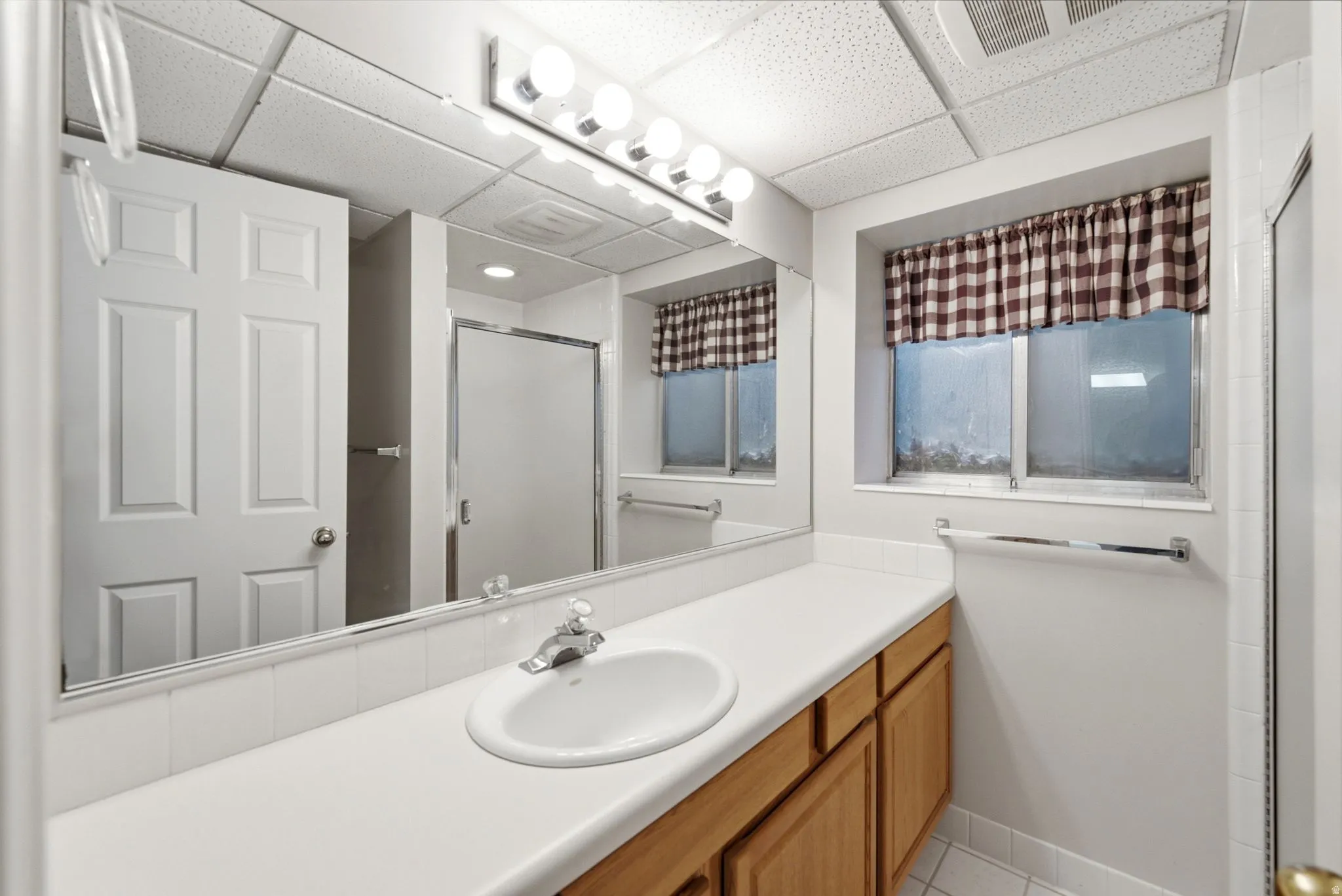 White vanity with a single basin sink, chrome faucet, and wood-finish cabinetry
