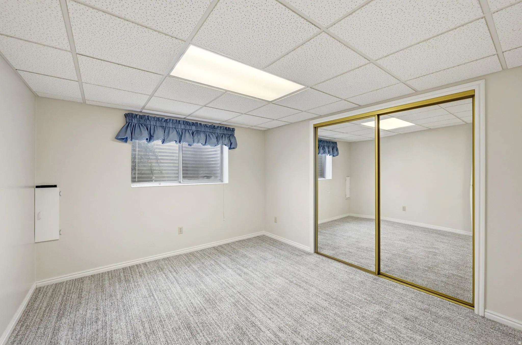 Recessed lighting, patterned carpeting, window with blinds, and mirrored sliding closet doors