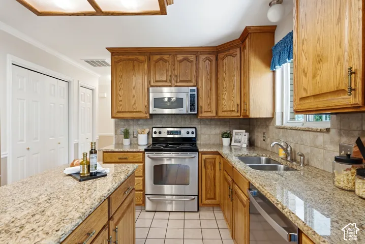 Kitchen featuring stainless steel appliances, granite countertops, tile flooring, and a tile backsplash