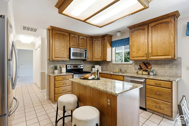 Kitchen featuring stainless steel appliances, a center island with granite countertop, and tiled flooring