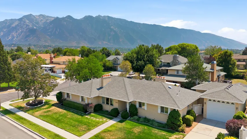 Expansive mountain range backdrop, established neighborhood, well-maintained landscaping, attached garage, and a concrete walkway