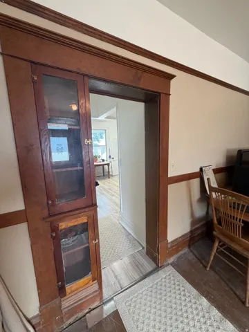 Integrated built-in wood-finish cabinetry with glass panel doors and brass hardware, featuring detailed crown molding and baseboards