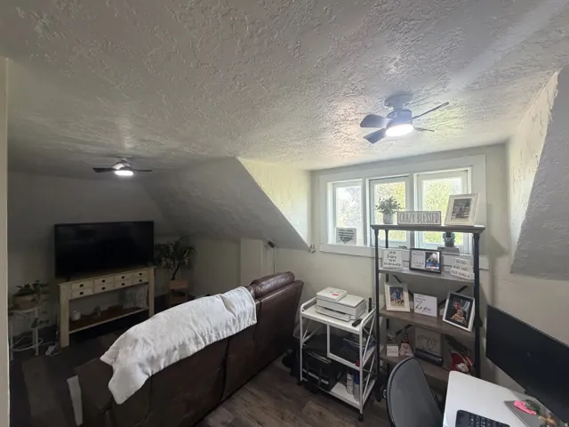 Attic room featuring sloped ceilings, wood-finish flooring, and multiple windows