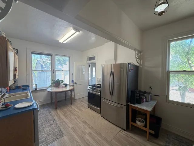 Kitchen featuring wood-finish flooring, two large windows, a stainless steel refrigerator, and a gas range