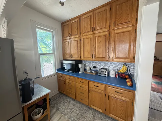 Kitchen featuring extensive wood cabinetry, blue countertops, and a mosaic tile backsplash