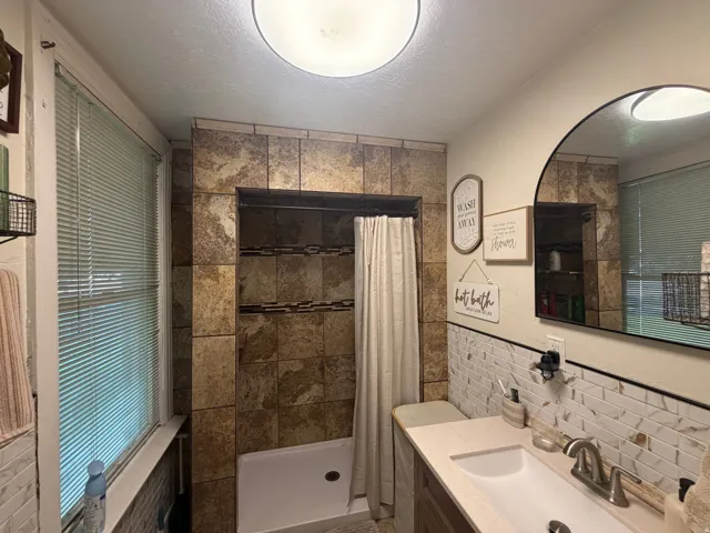 Bathroom featuring a walk-in shower with stone-look tile surround and decorative accent banding