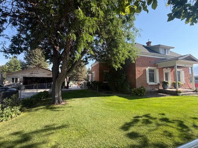 Brick exterior featuring white window trim, a covered front porch, and a dormer