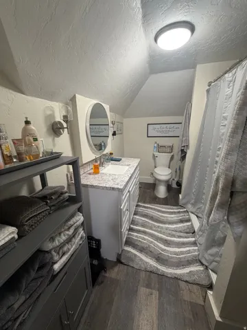 Bathroom featuring a white vanity with a speckled countertop, a round mirror, and a wall-mounted light fixture
