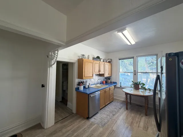 Kitchen featuring wood-finish flooring, oak cabinetry, blue countertops, and a tiled backsplash