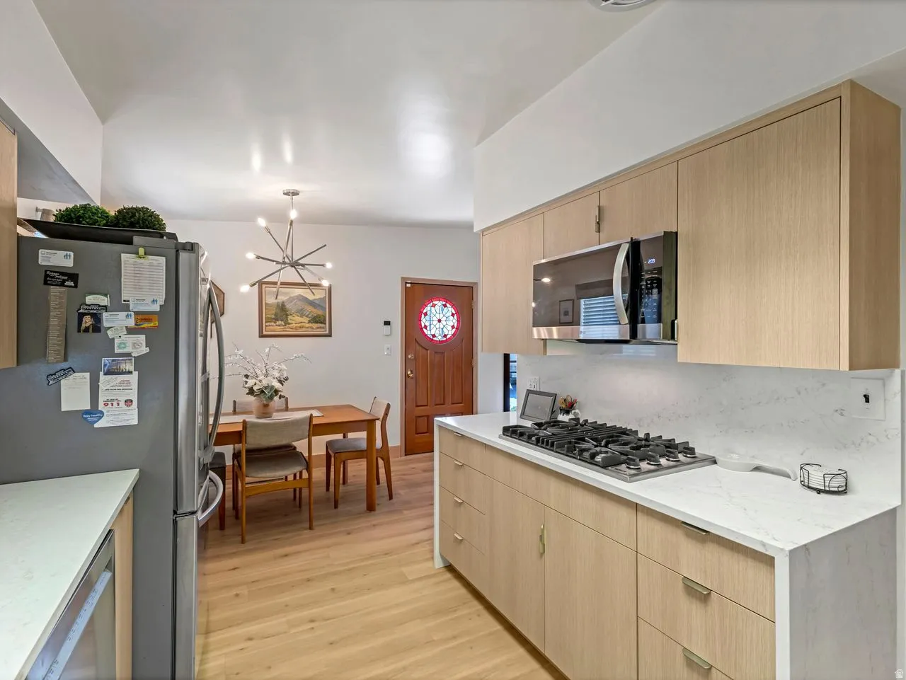 Modern kitchen featuring light wood-finish cabinetry, white countertops, and stainless steel appliances