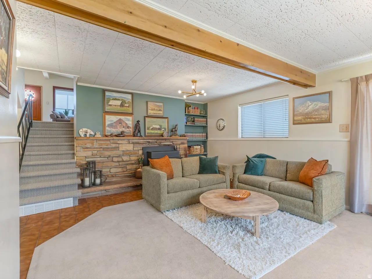 Stone-accented fireplace with hearth, wood-finish ceiling beams, and built-in shelving