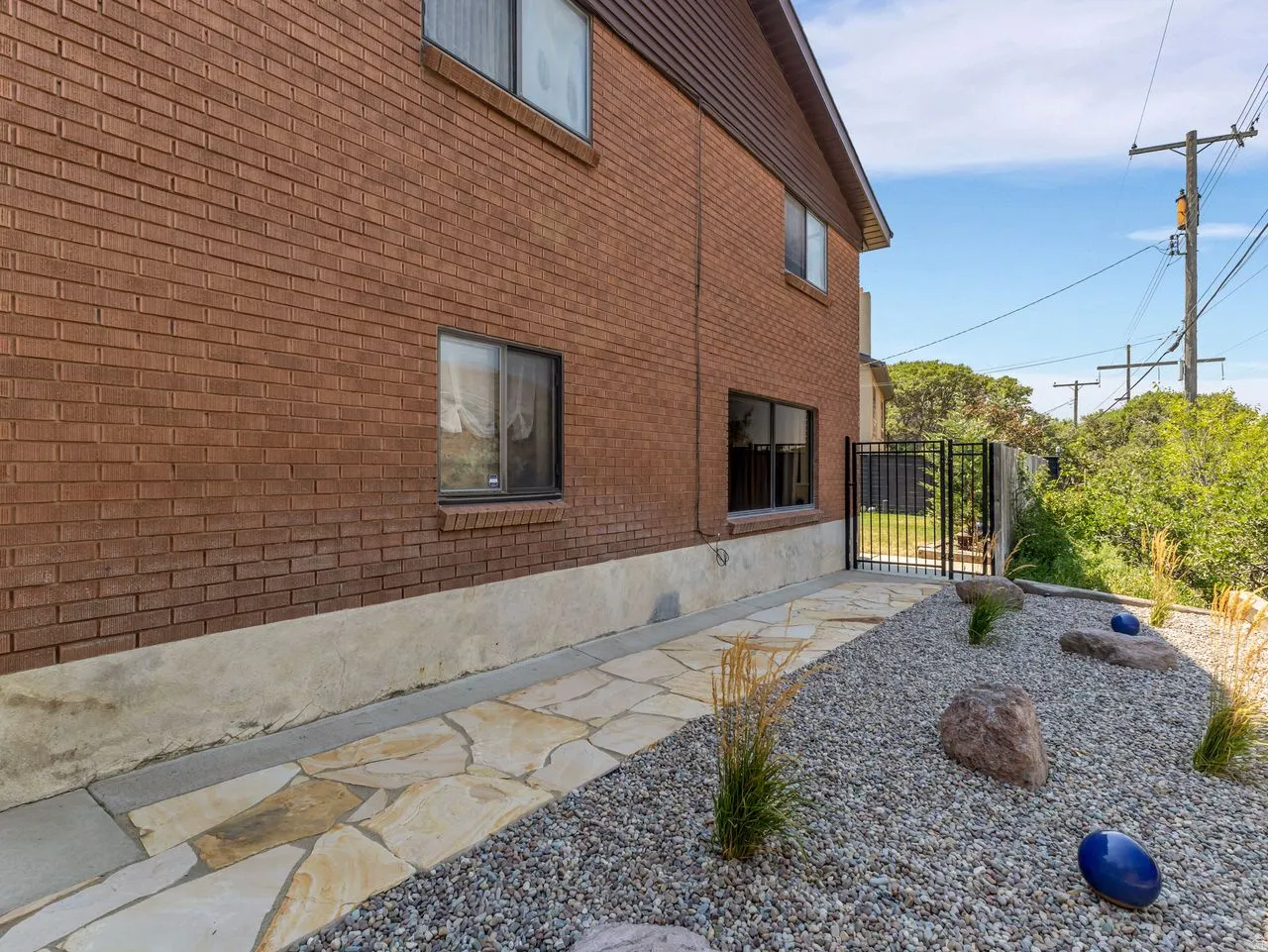 Brick exterior with a concrete foundation, flagstone pathway, and gravel landscaping