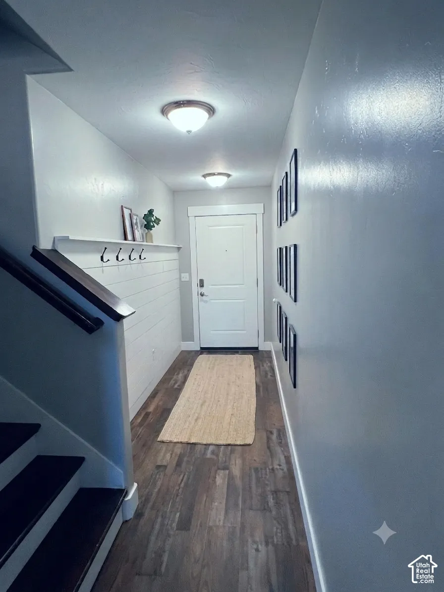 Entryway featuring wood-finish flooring, a white shiplap accent wall with integrated shelving and hooks, and overhead flush-mount lighting fixtures