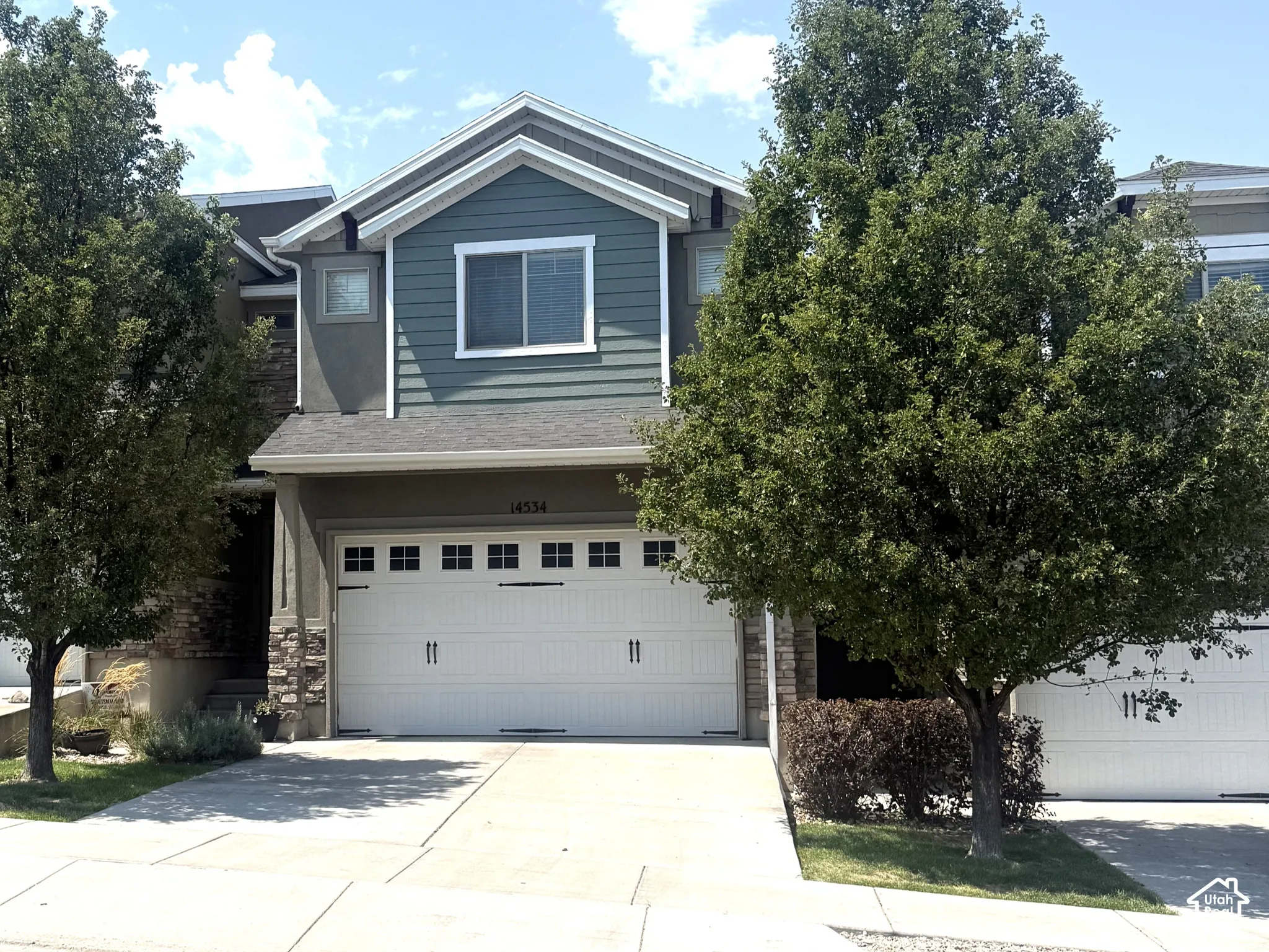 Two-car garage with panel doors, stone facade accents, and light-colored siding