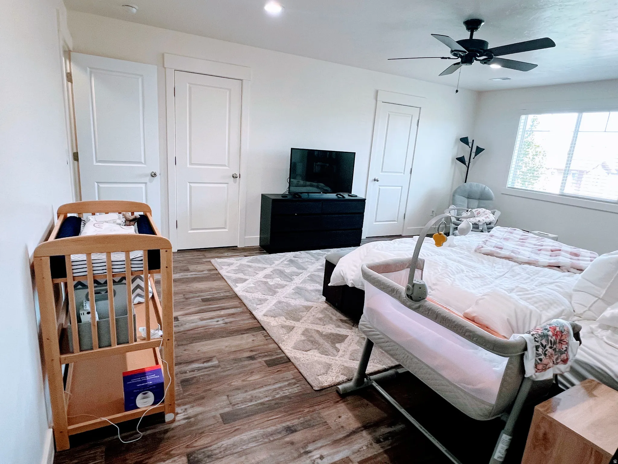 Wood-finish flooring with a ceiling fan light fixture and white interior doors