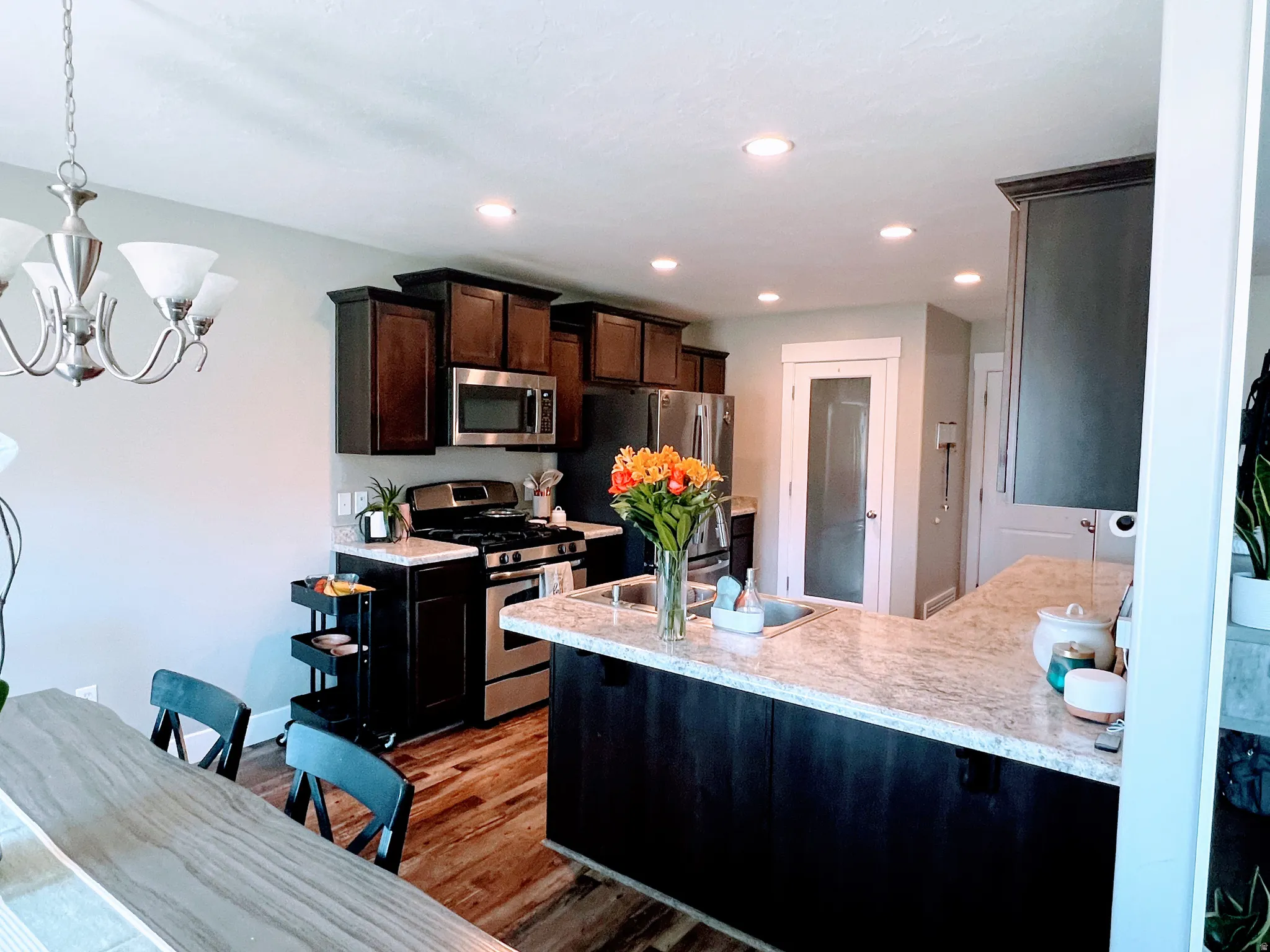 Kitchen featuring dark wood-finish cabinetry, stainless steel appliances, a light-toned countertop, and recessed lighting