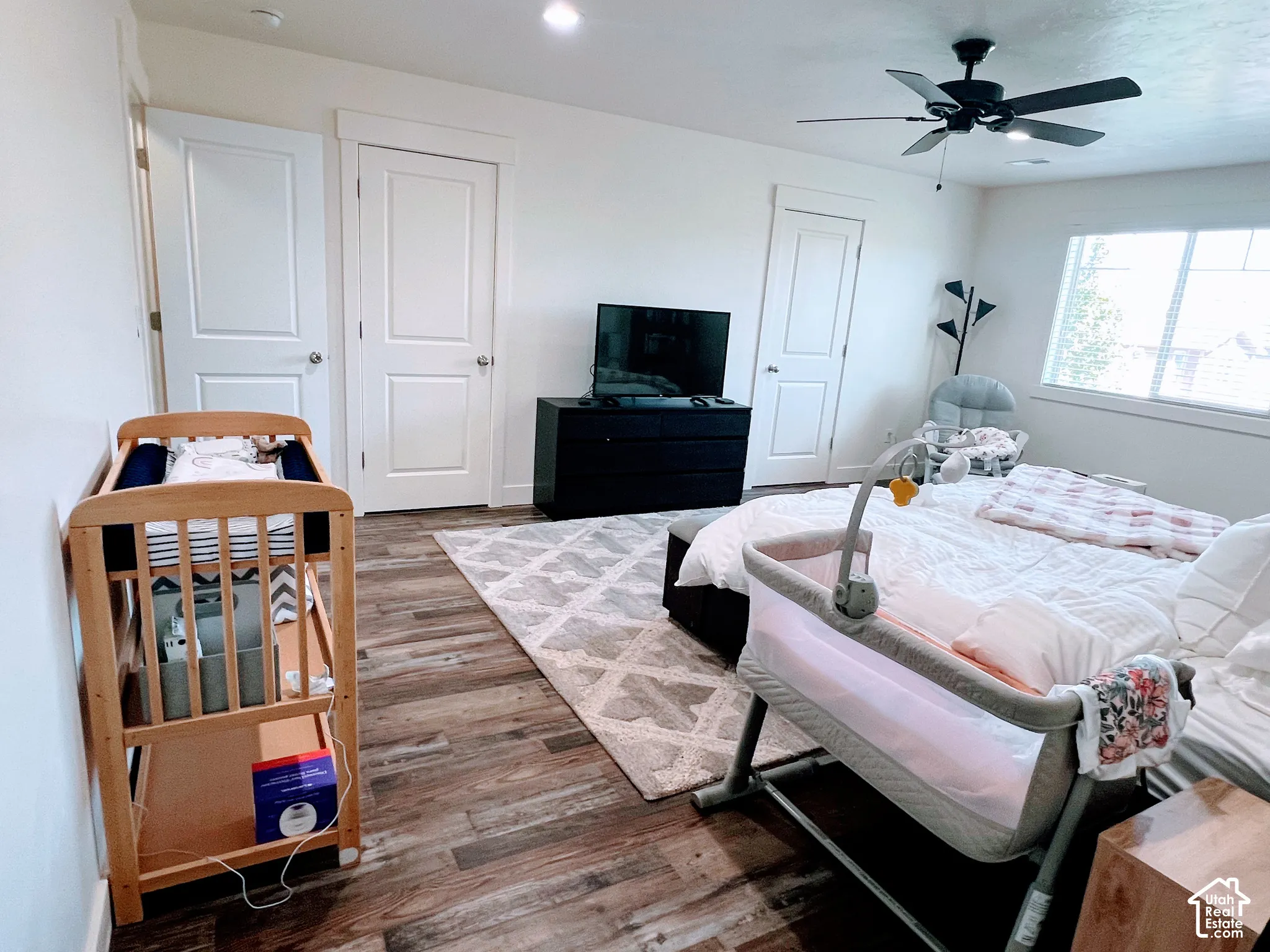 Wood-finish flooring with a ceiling fan light fixture and white interior doors