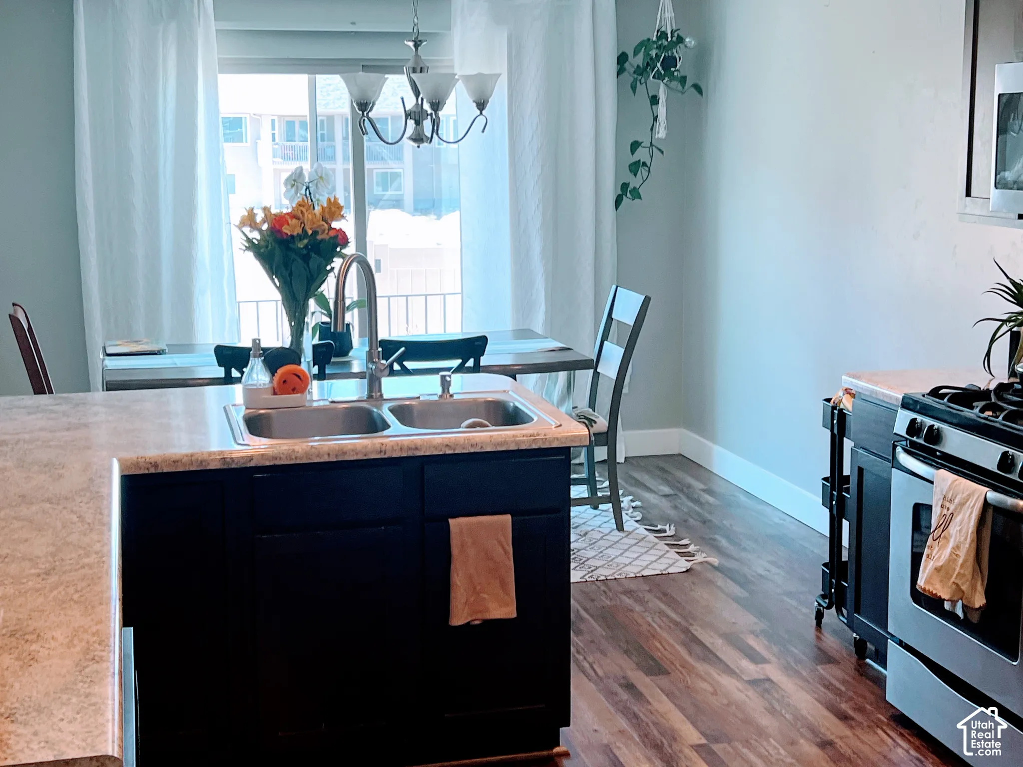 Kitchen featuring a double basin stainless steel sink, dark wood-finish cabinetry, wood-finish flooring, and a stainless steel oven/range