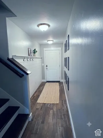 Entryway featuring wood-finish flooring, a white shiplap accent wall with integrated shelving and hooks, and overhead flush-mount lighting fixtures