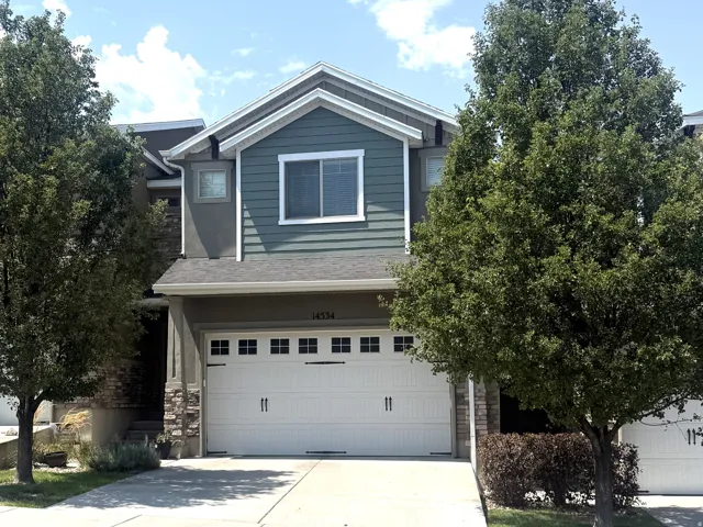 Two-car garage with panel doors, stone facade accents, and light-colored siding