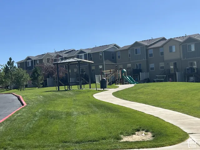 Community green space featuring a paved walkway, covered picnic area, and a children's play structure