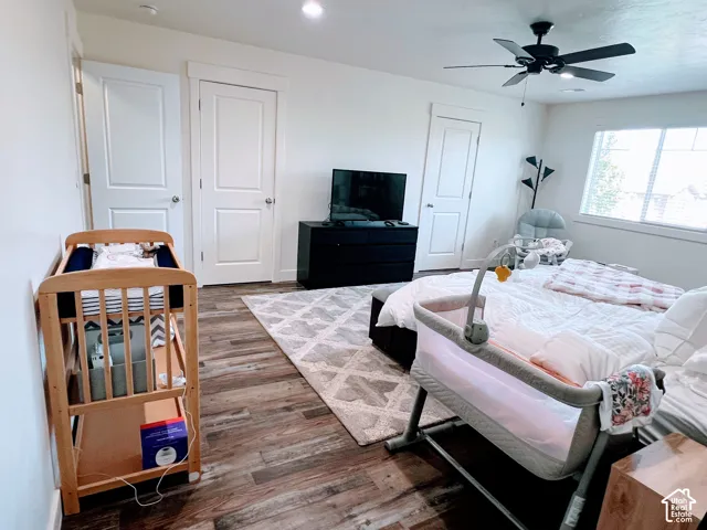Wood-finish flooring with a ceiling fan light fixture and white interior doors