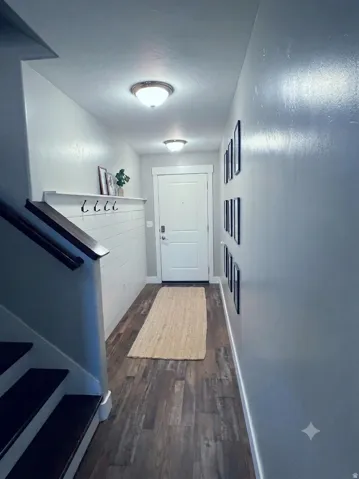Entryway featuring wood-finish flooring, a white shiplap accent wall with integrated shelving and hooks, and overhead flush-mount lighting fixtures