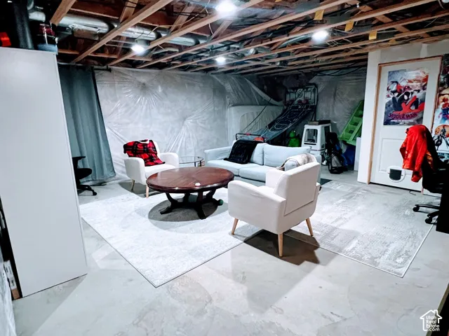 Unfinished basement space featuring exposed ceiling joists and concrete flooring