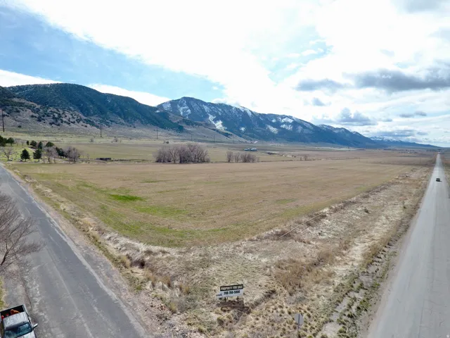 Expansive land parcel with surrounding mountains, paved road frontage, and natural vegetation