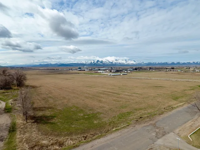 Expansive land parcel with distant mountain ranges and scattered residential structures