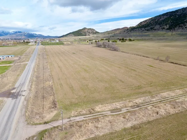 Expansive open land with distant mountainous terrain, a paved road, and a distant town center