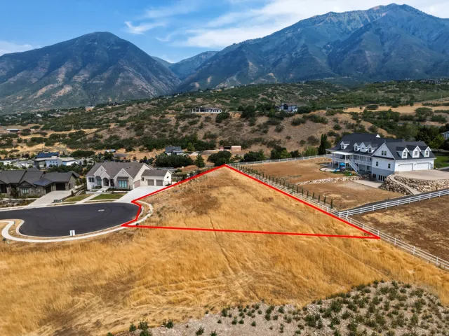 Expansive undeveloped lot with sloping terrain, bordering a paved cul-de-sac