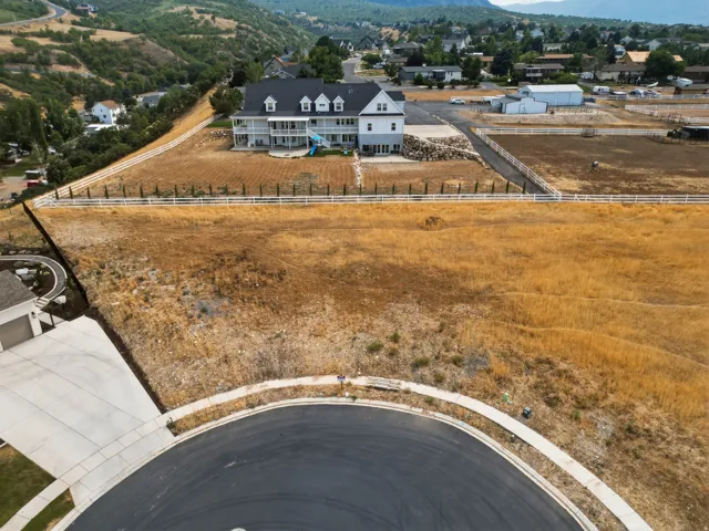 Expansive property with a white fence perimeter, featuring a paved cul-de-sac and concrete sidewalks