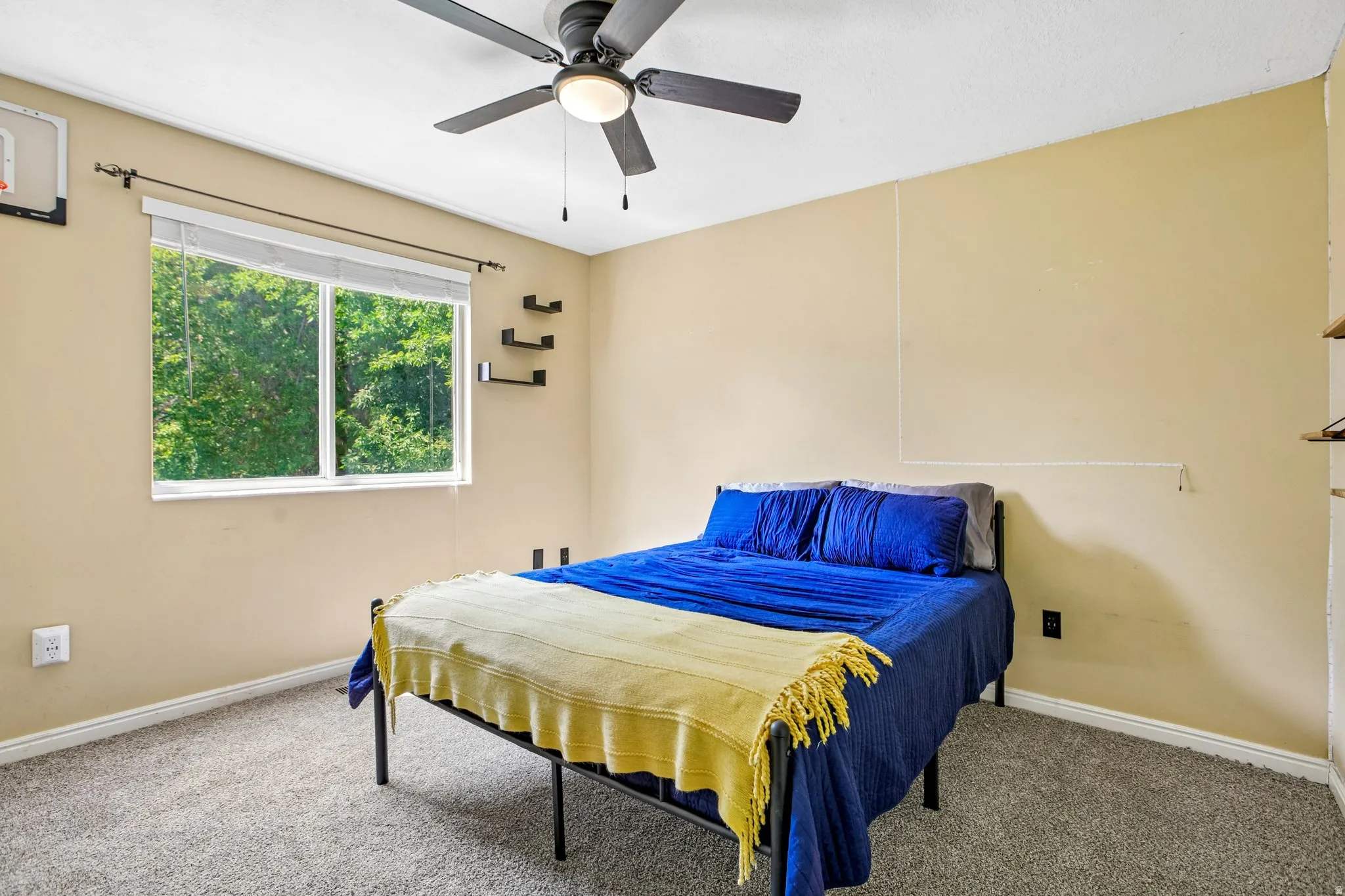 Recessed window with white blinds, neutral wall paint, ceiling fan with integrated lighting, and wall-mounted shelving
