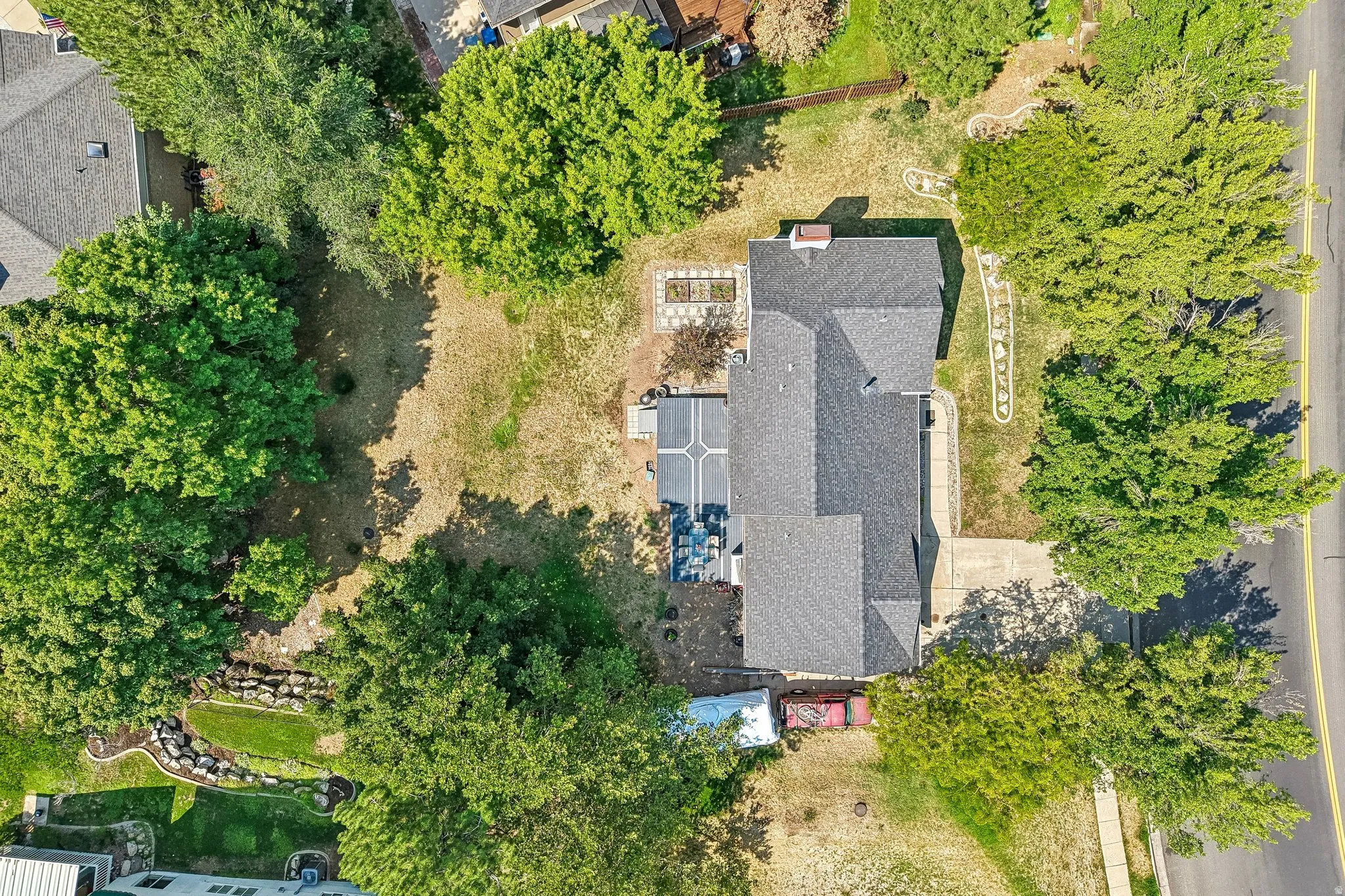 Pitched roofline, concrete driveway, mature trees, paved patio, landscaped rock features