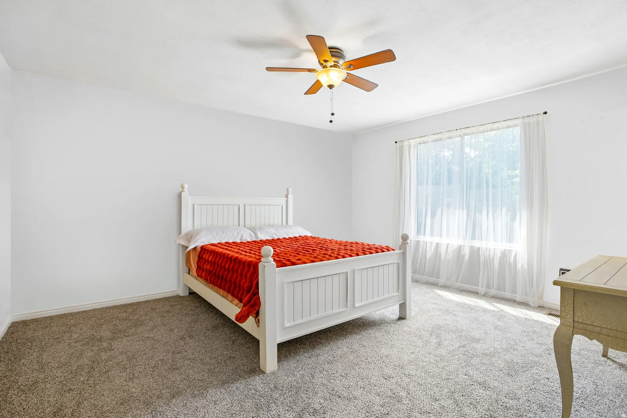 Recessed lighting, ceiling fan with wood-finish blades, and broad window create an illuminated space