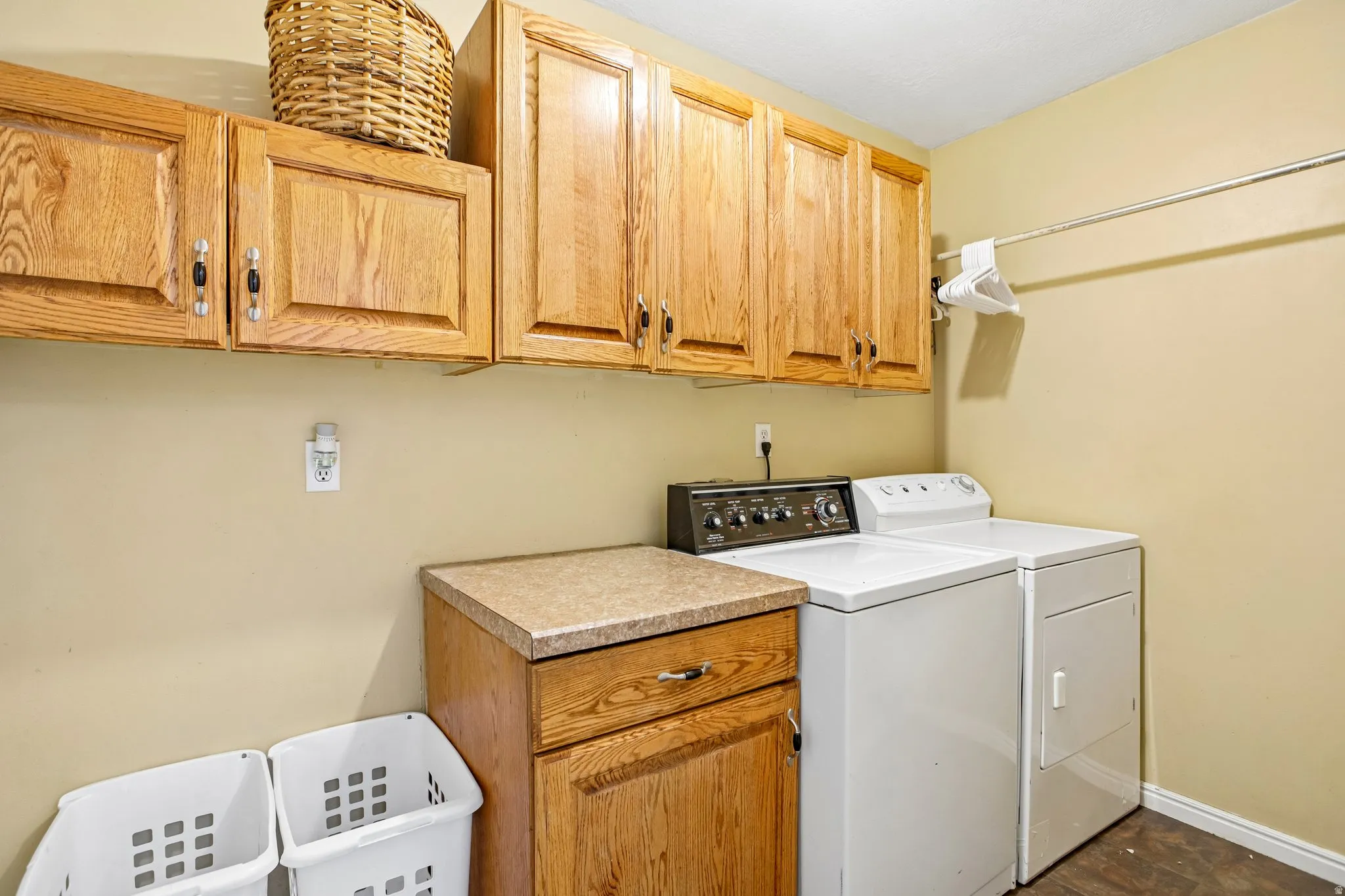 Upper cabinetry with wood finish, countertop with speckled finish, and a clothing rod