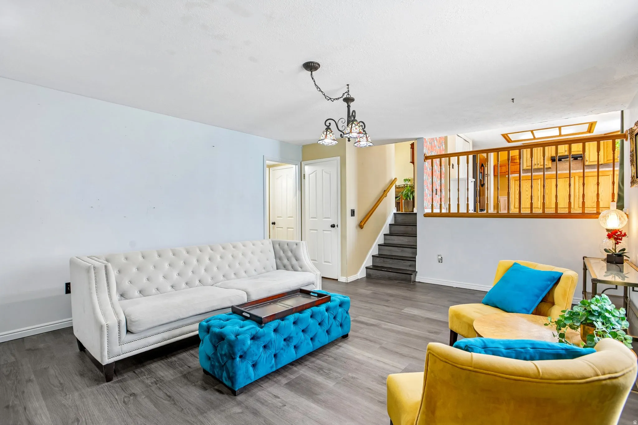 Wood-finish flooring, staircase with dark treads and light wood railing, interior doors with dark hardware, and a semi-flush mount chandelier
