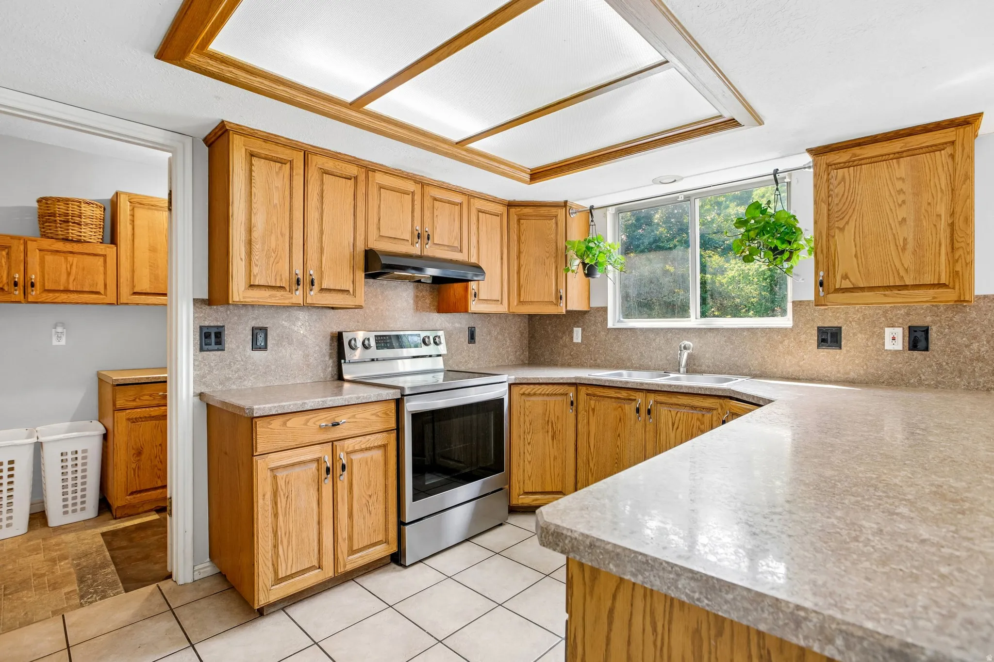 Expansive counter space, wood-finish cabinetry, stainless steel range, and tile flooring