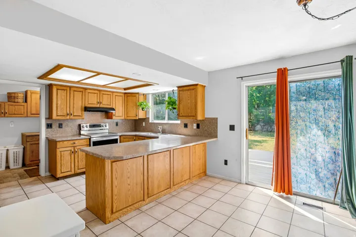 Kitchen featuring warm wood cabinetry, neutral countertops, and a tiled backsplash