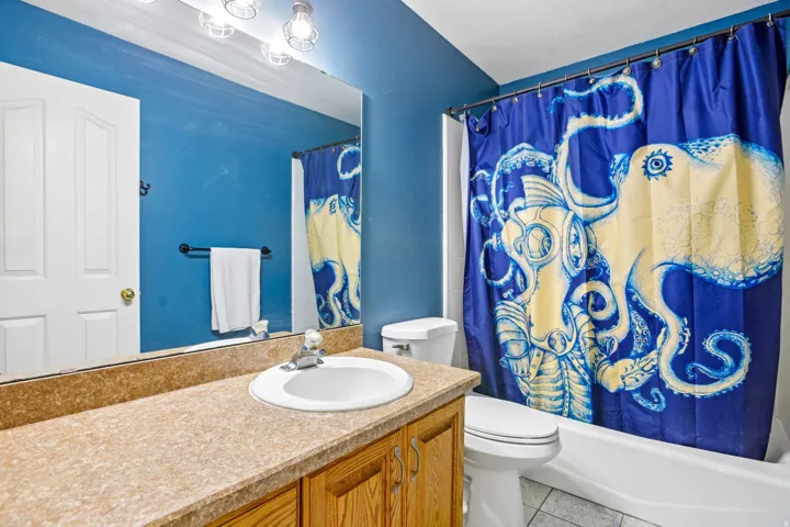 Bathroom featuring a single vanity with wood-finish cabinetry, a large wall-mounted mirror, and an integrated shower/tub combination
