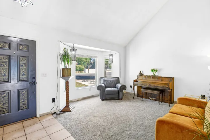 Vaulted ceilings, bay window, carpeted flooring, and entryway tile