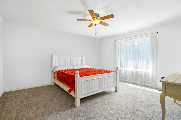 Recessed lighting, ceiling fan with wood-finish blades, and broad window create an illuminated space