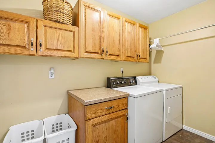 Upper cabinetry with wood finish, countertop with speckled finish, and a clothing rod