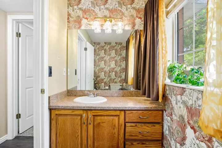 Vanity with wood-finish cabinetry, integrated sink, and laminate countertop